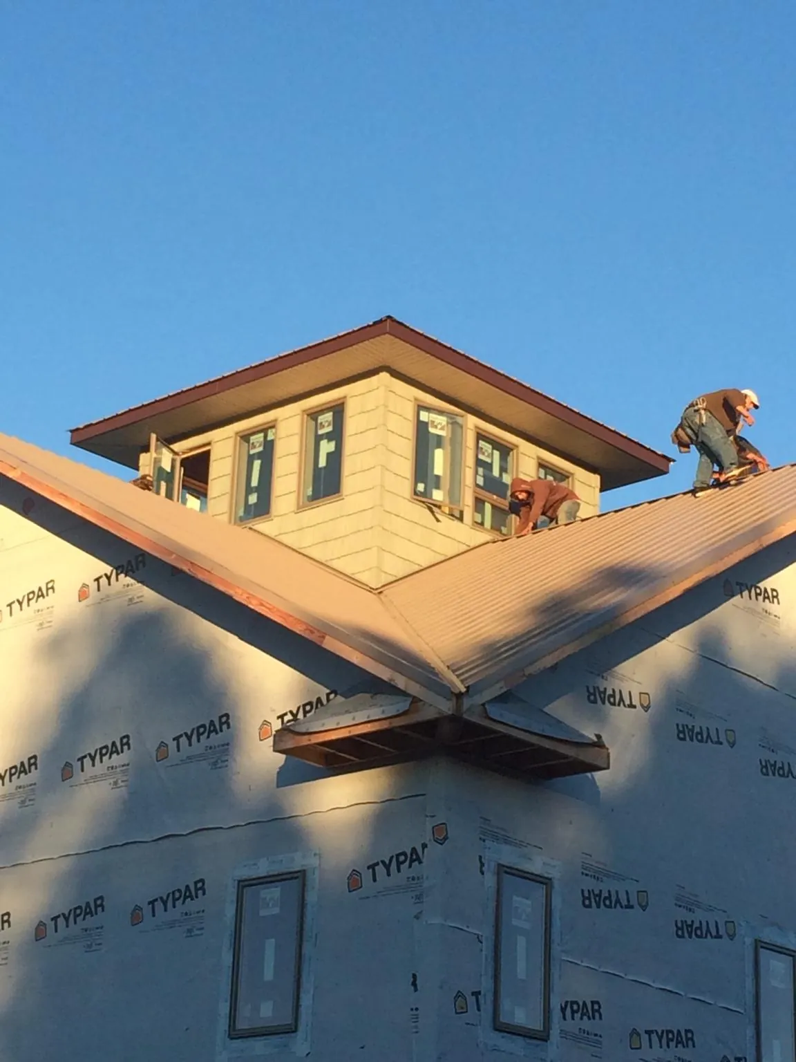 Roofers working around a rooftop cupola on a new metal roof at sunset — Roof Waterproofing in Monrovia by Roofing Brothers